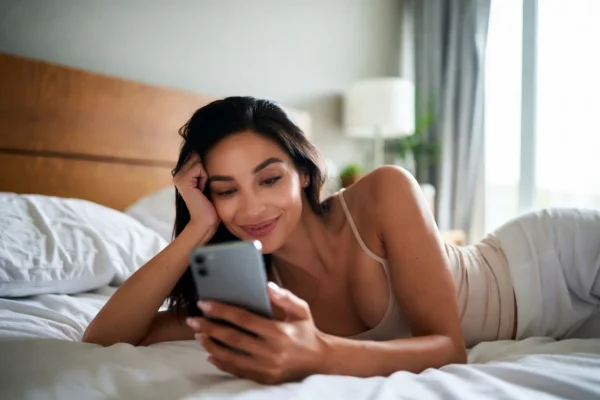 Woman enjoying a random online chat while relaxing on her bed