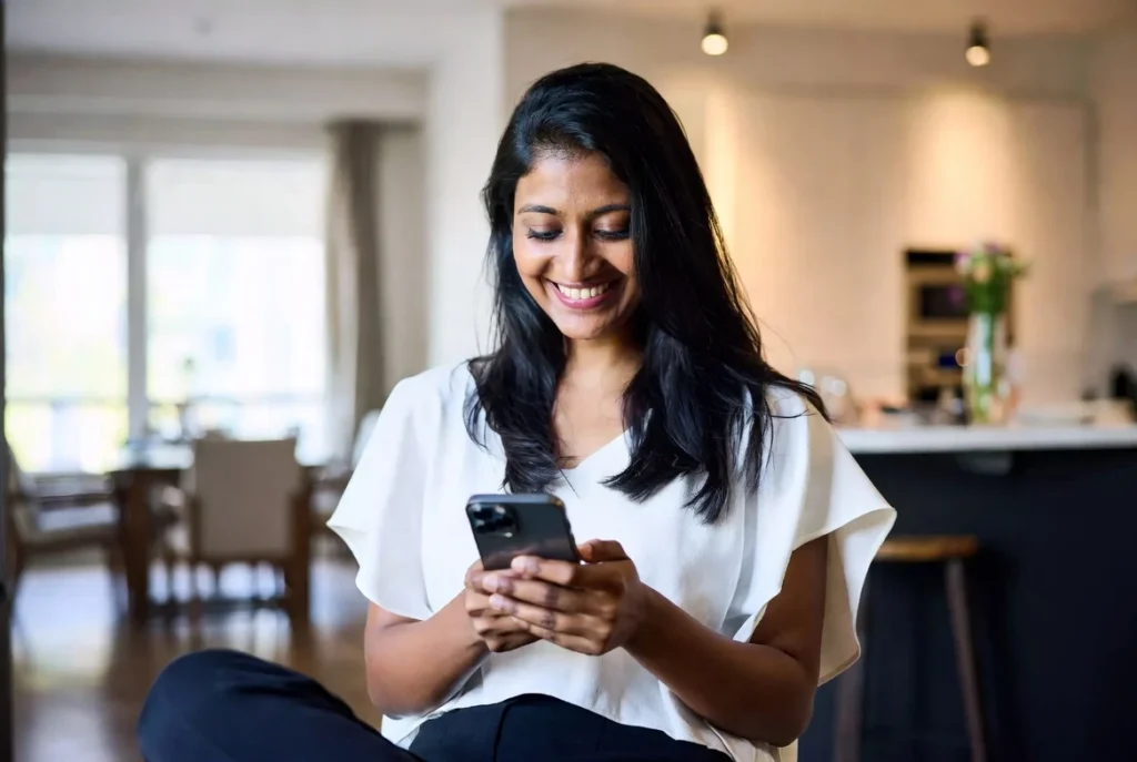 Woman using a smartphone for a private desi chat at home